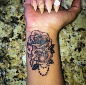 Rosen Tattoo am Handgelenk mit Taube und Rosenkranz